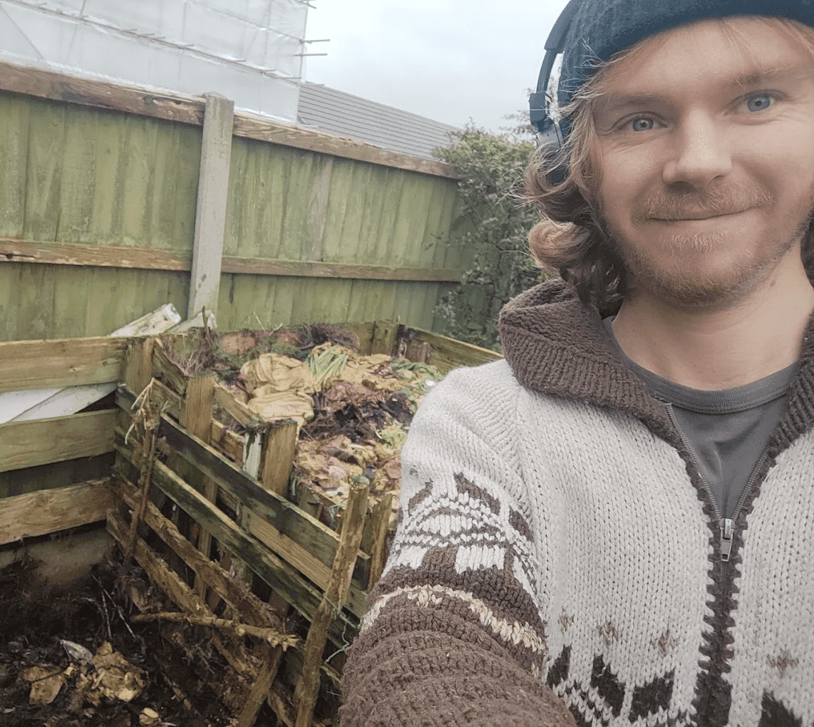 The gardener smiling beside a compost bay he has built in a Wirral garden