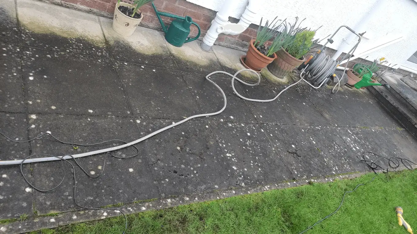 A large paved patio being cleaned, with algae and moss lifted from the slabs