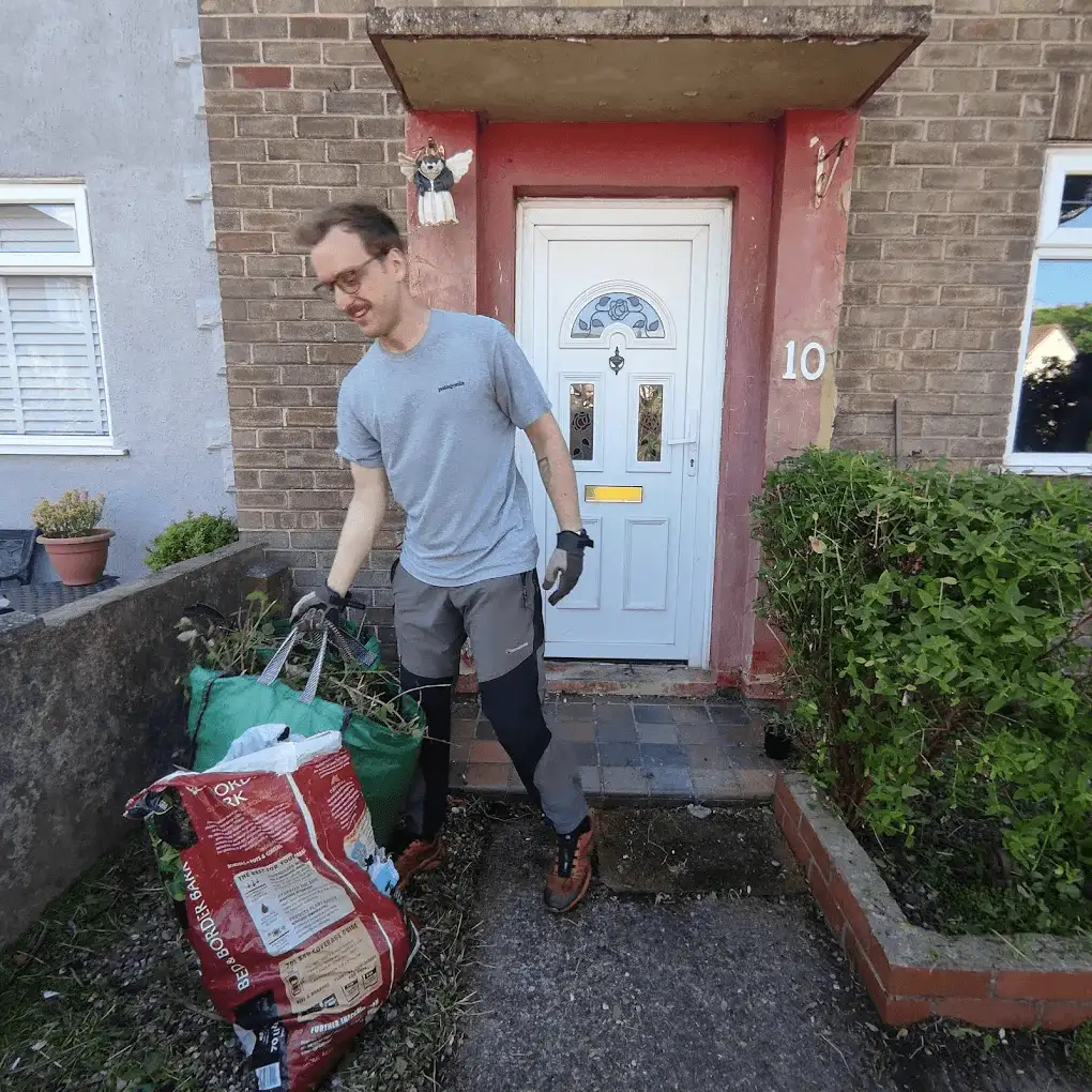 The gardener carrying bags of garden waste away from a front garden